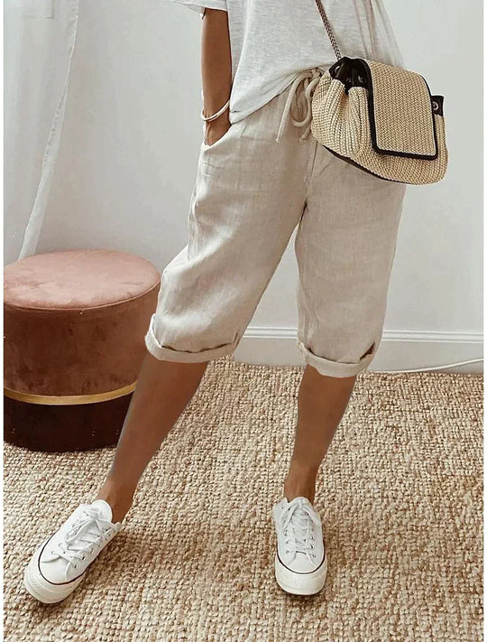 Kvinna som bär ljusa beige dambyxor med vita sneakers och väska
