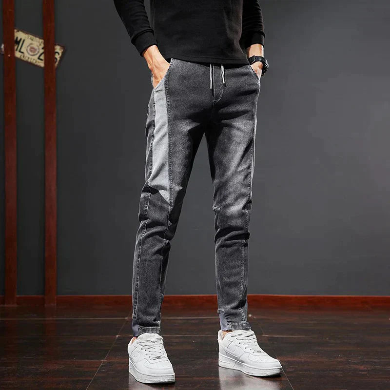 Man bär svarta Mason slim fit jeans med svart tröja och vita sneakers