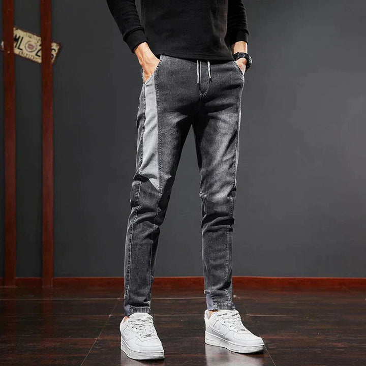 Man bär svarta Mason slim fit jeans med svart tröja och vita sneakers