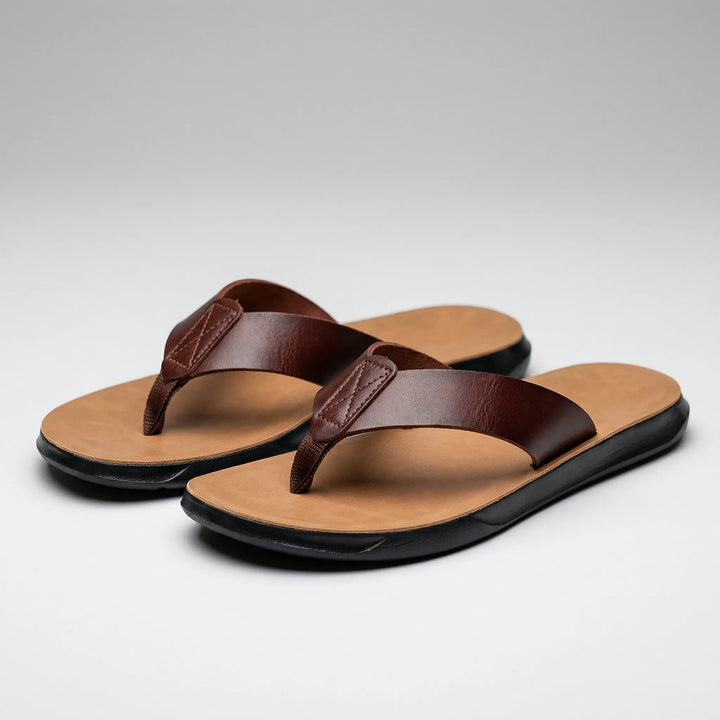 Ett par bruna herrflip-flops uppställda på ljus bakgrund