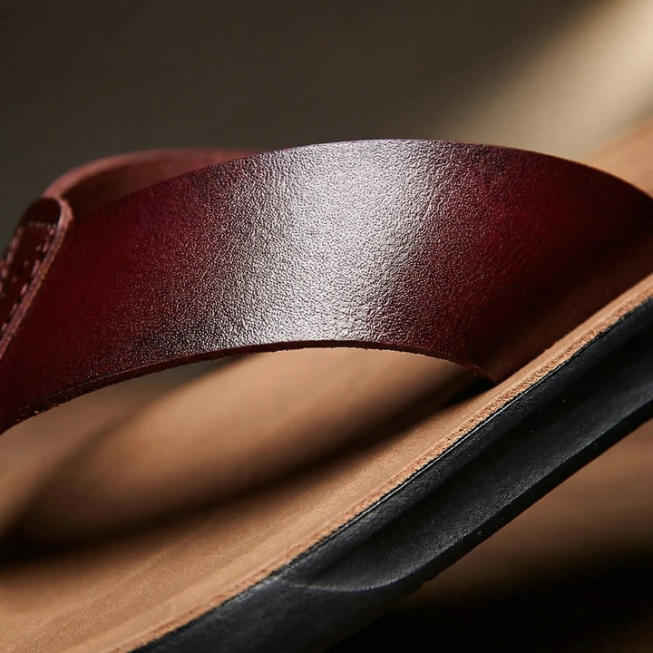 Närbild på den mörkröda remmen och texturerade fotbädden på sandalerna