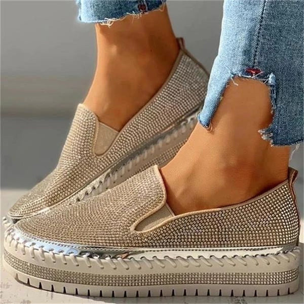 Närbild på guldiga glittrande slip-on-skor för damer