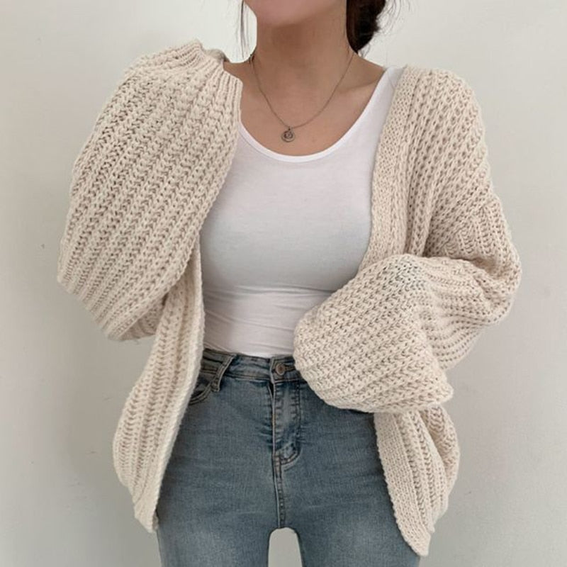 Kvinna i krämvit chunky stickad cardigan med öppen front