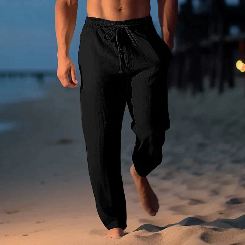 Svart modell av smala sommarbyxor med dragsko för herrar på stranden