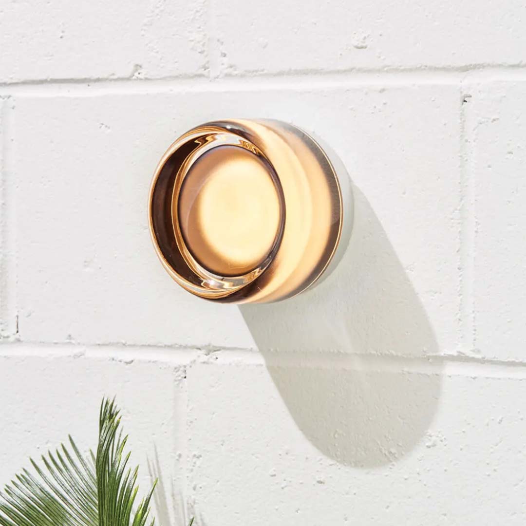 Närbild på en stilren amberfärgad dimple-vägglampa monterad på vit tegelvägg