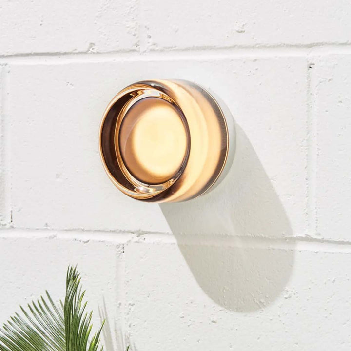 Närbild på en stilren amberfärgad dimple-vägglampa monterad på vit tegelvägg