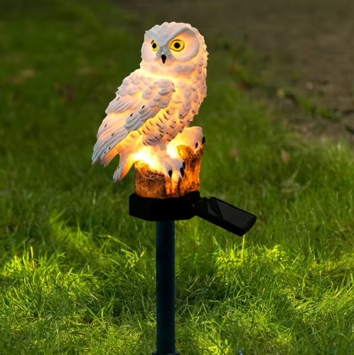 Vit solcellsuggla trädgårdslampa som lyser upp i gräset