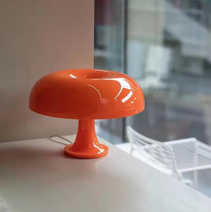 Modern orange designer LED svamplampa placerad på en vit yta vid ett fönster
