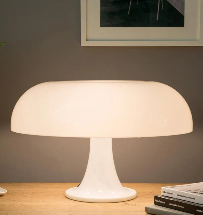 Elegant vit LED svamplampa på ett träbord framför en grå vägg med tavla
