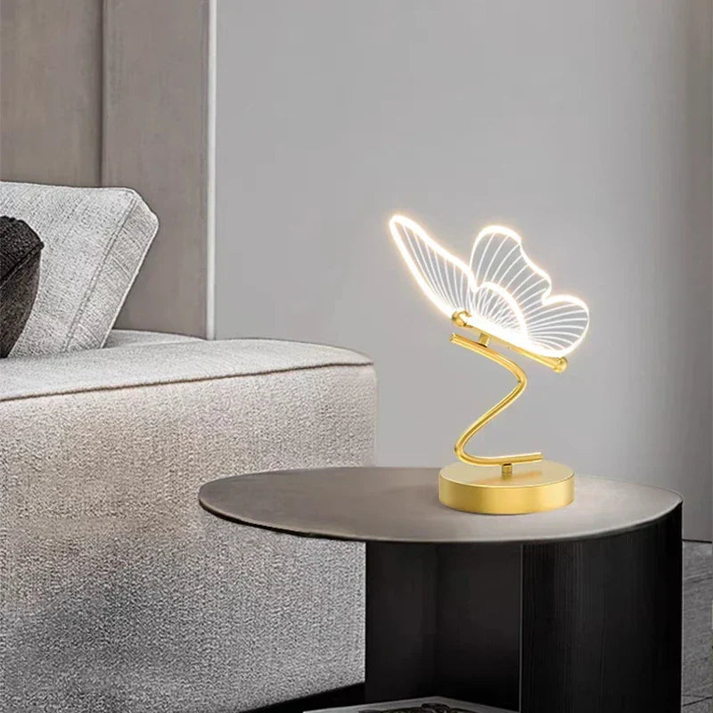 Guldéfärgad bordslampa Lunavia Fjäril LED 6W tänd i ett mörkt rum