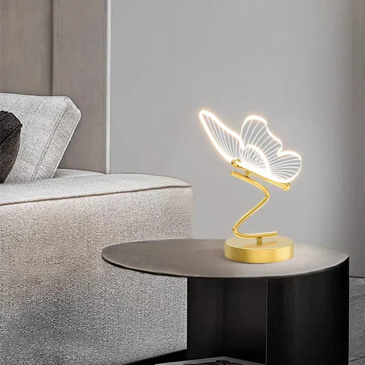 Guldéfärgad bordslampa Lunavia Fjäril LED 6W tänd i ett mörkt rum