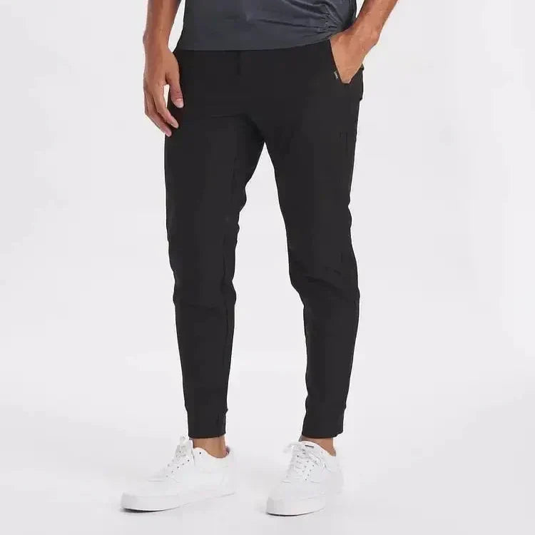 Man i svarta slim-fit-byxor med raka ben och vita sneakers