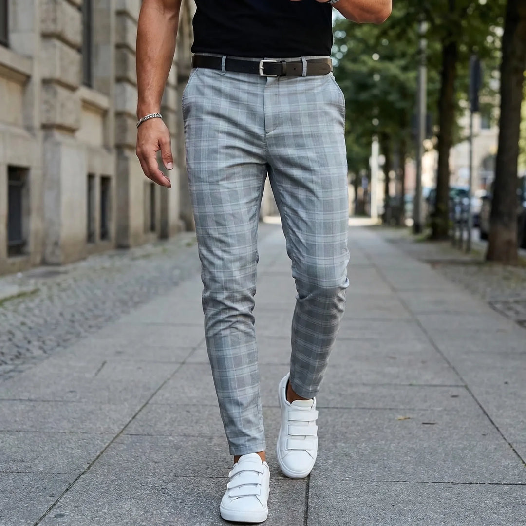 Man i rutiga slim fit ankellånga byxor med vita sneakers utomhus