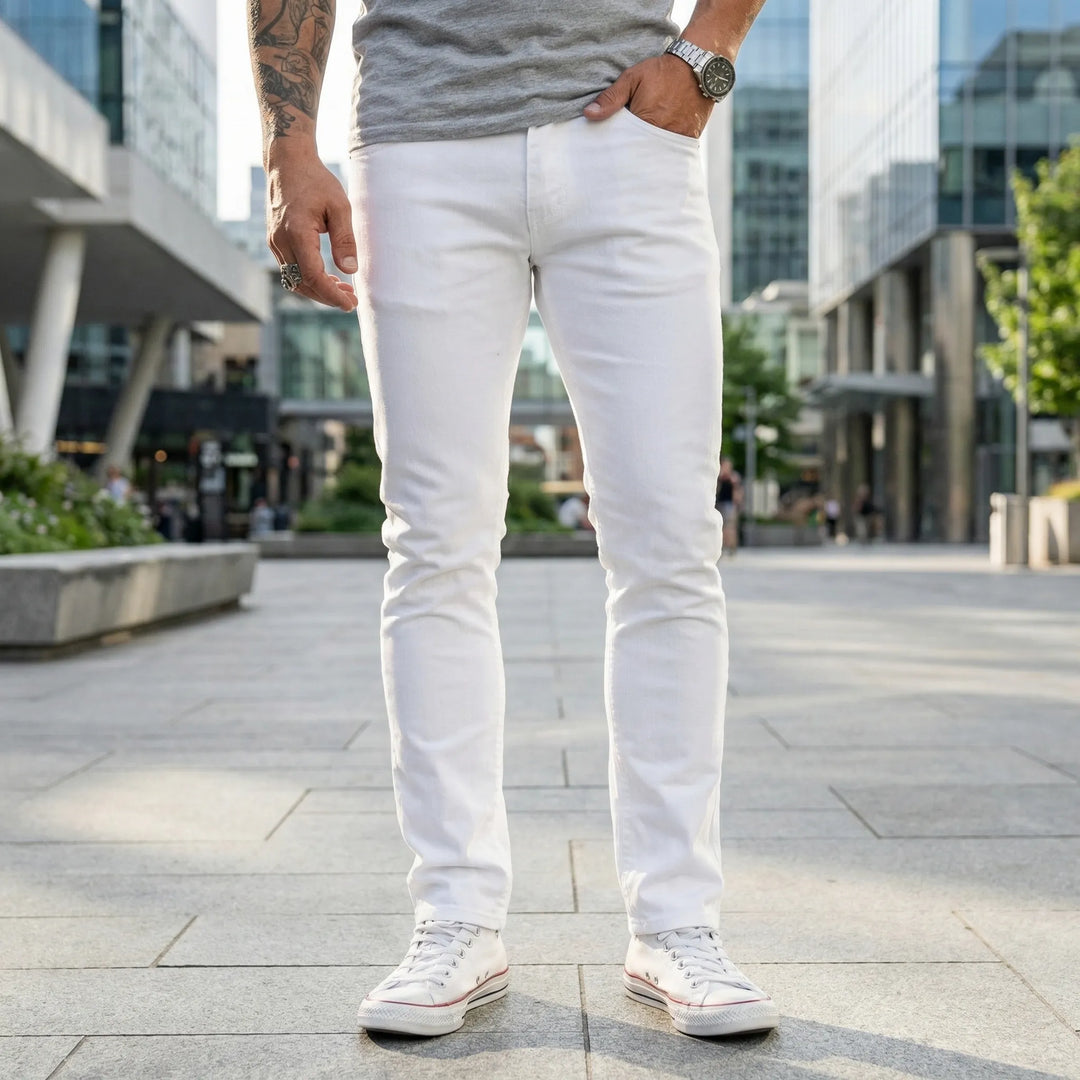 Man i vita slim fit-jeans stående utomhus i stadsmiljö