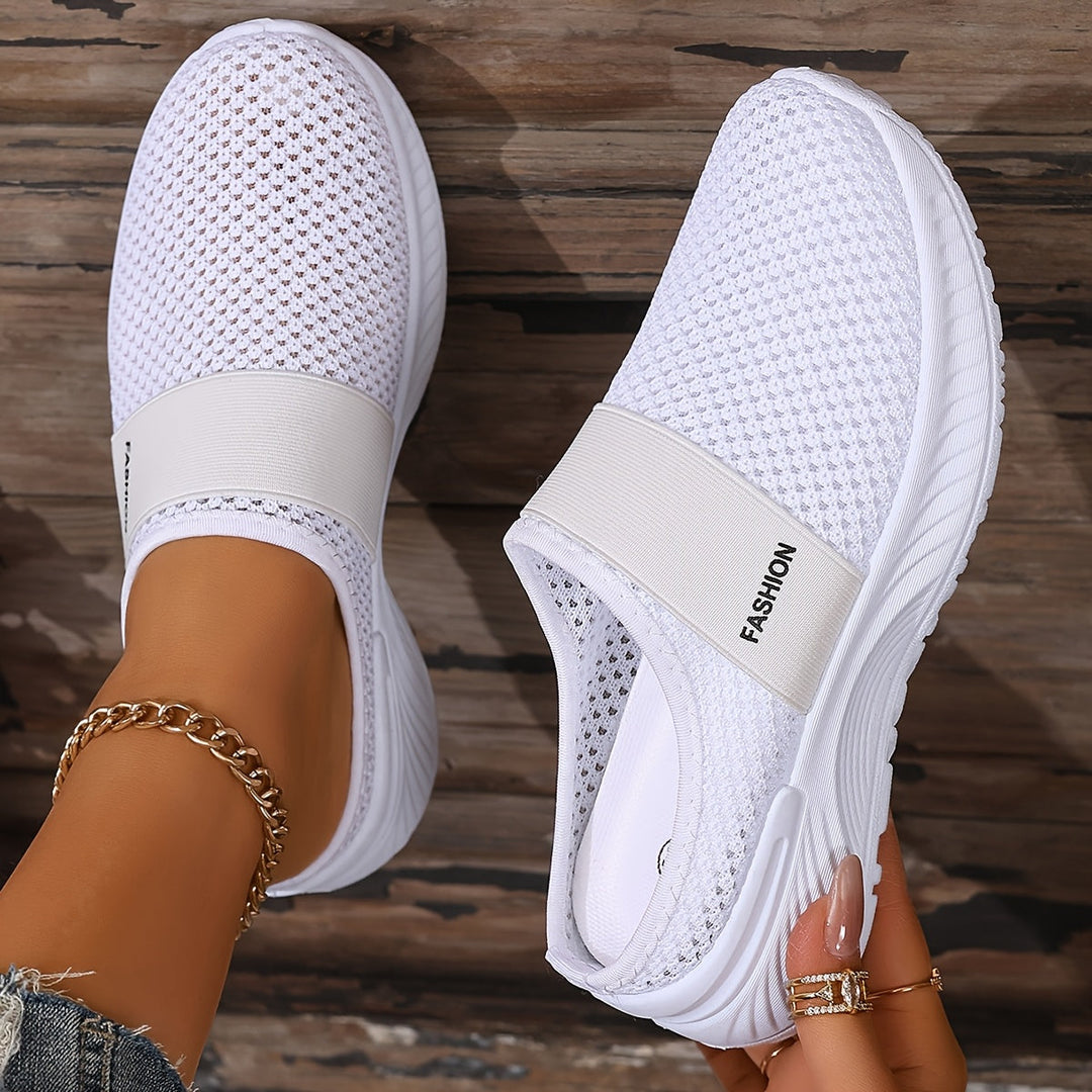 Vit ventilerande slip-on-sneaker för dam hållen i handen