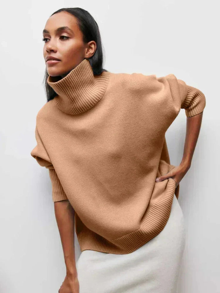 Modell i camel-färgad oversized stickad tröja med rullhals