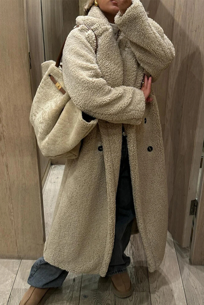 Kvinna som bär en lång beigefärgad teddykappa utomhus
