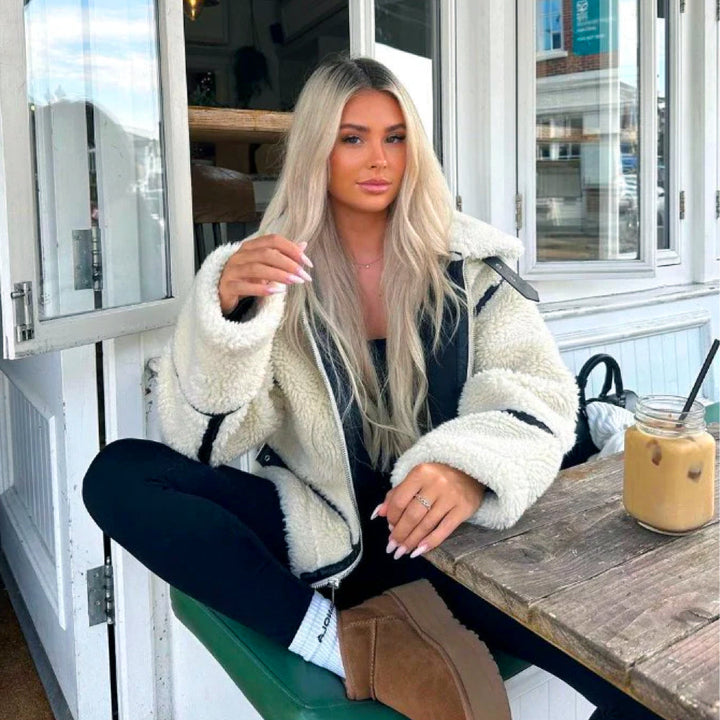 Kvinna som bär en trendig oversized teddyjacka i bikerstil utomhus