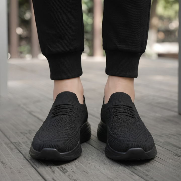 Person som bär svarta bekväma slip-on skor utomhus
