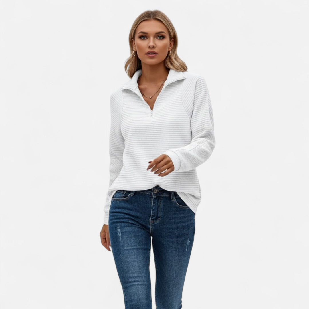 Modell som bär vit tröja med dragkedja och blå jeans
