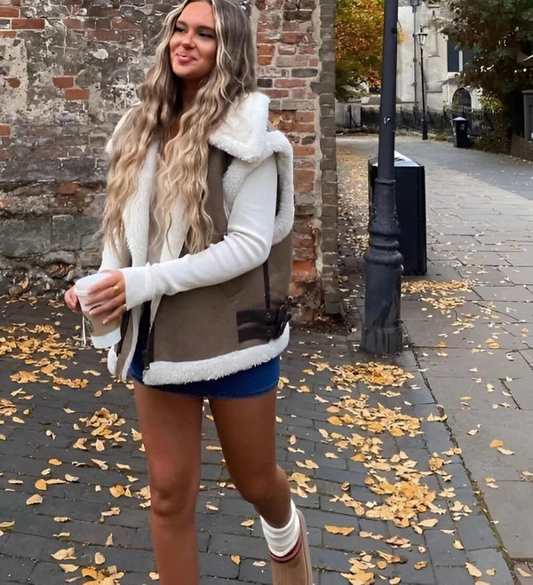 Kvinna med blond hår som promenerar i en brun och vit damväst