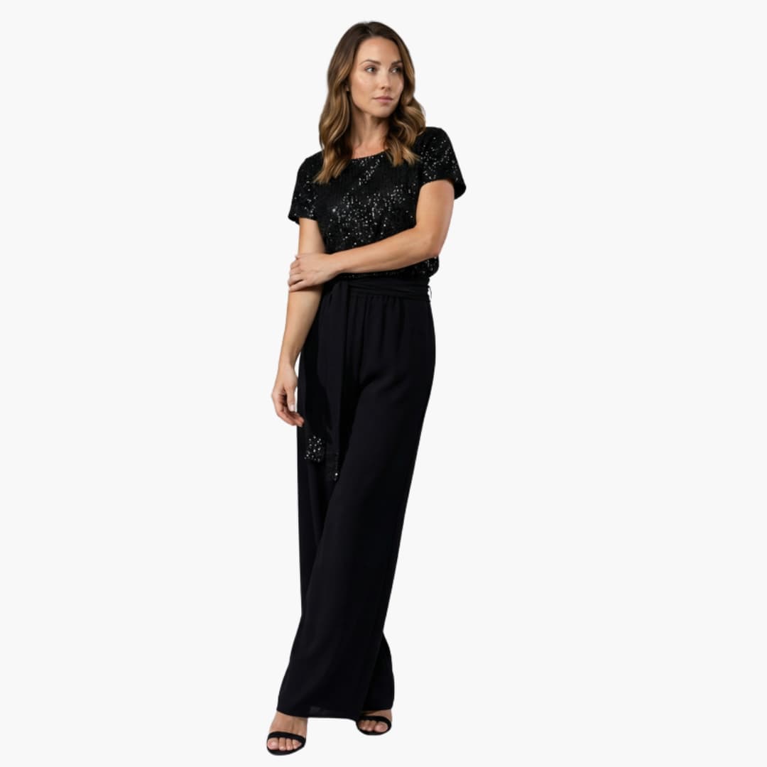Kvinna i svart paljettjumpsuit med vida ben