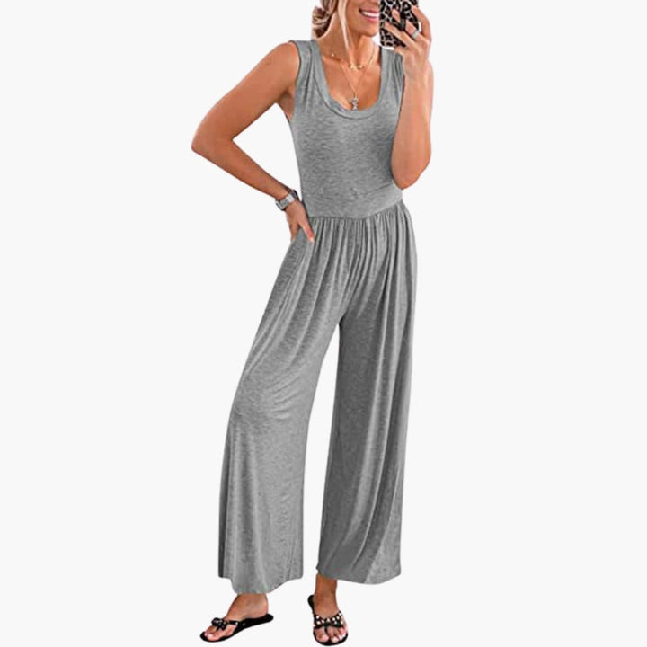 Kvinna i grå ärmlös jumpsuit med vida ben och rund halsringning