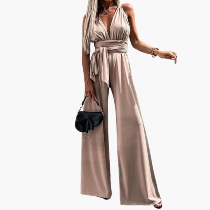 Kvinna som bär en elegant aprikosfärgad ärmlös byxdress med vida ben och midjebälte