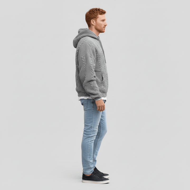 Profilbild av man i grå strukturstickad huvtröja mot ljus bakgrund