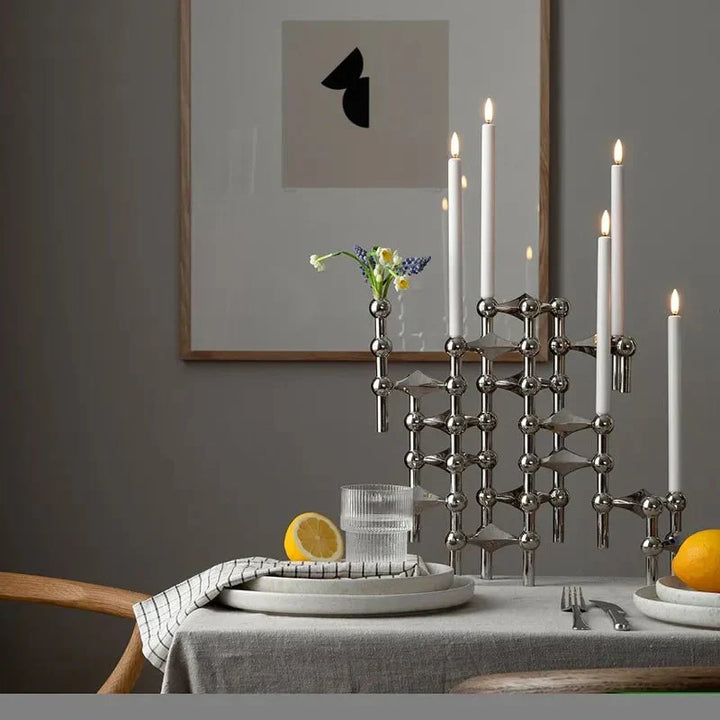Silverfärgad ljusstake i metall med tända ljus i en elegant miljö