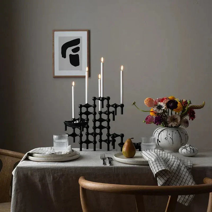 Svart ljusstake i metall placerad på ett dukat middagsbord