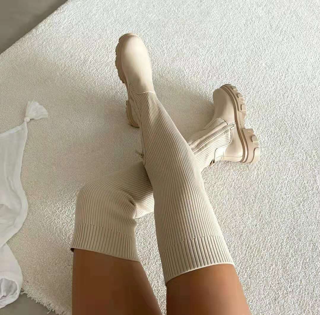 Beige knähöga damstövlar i mjuk miljö med texturerad matta