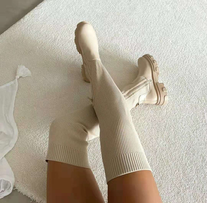 Beige knähöga damstövlar i mjuk miljö med texturerad matta
