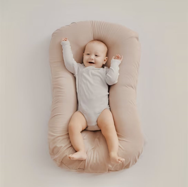 Ergonomisk sovstödskudde för baby placerad på en neutral bakgrund