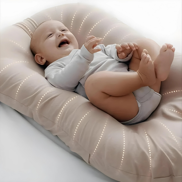 Glad baby som vilar bekvämt på den ortopediska babykudden i beige