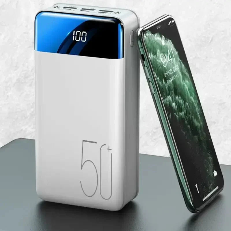 Vit bärbar powerbank bredvid en smartphone på ett bord