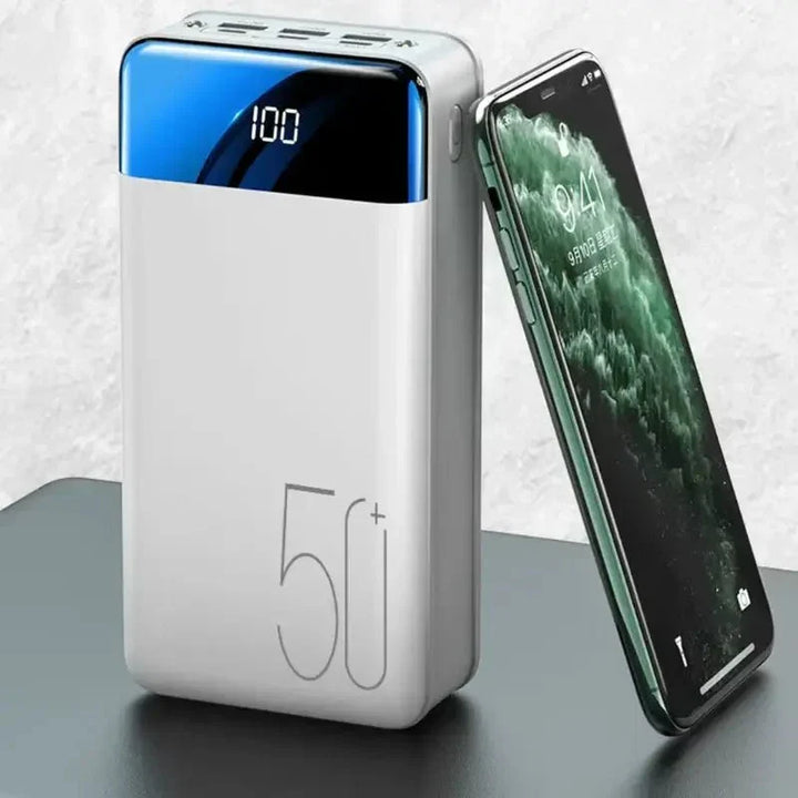 Vit bärbar powerbank bredvid en smartphone på ett bord