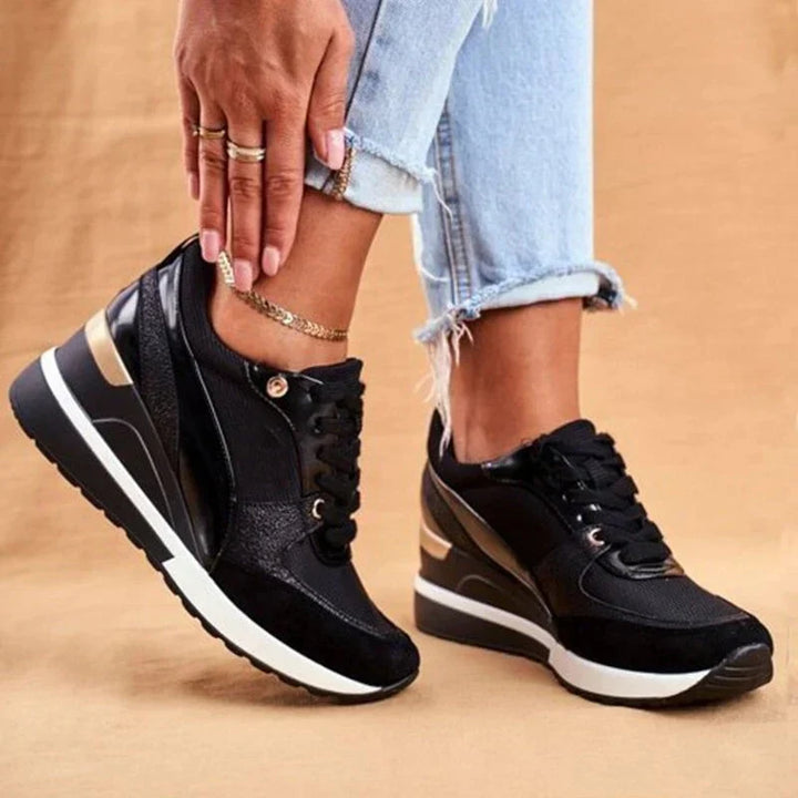 Modell som visar svarta sneakers med guldfärgade detaljer