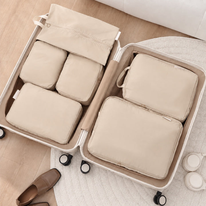 Beige packpåsar placerade i en öppen resväska för perfekt organisering