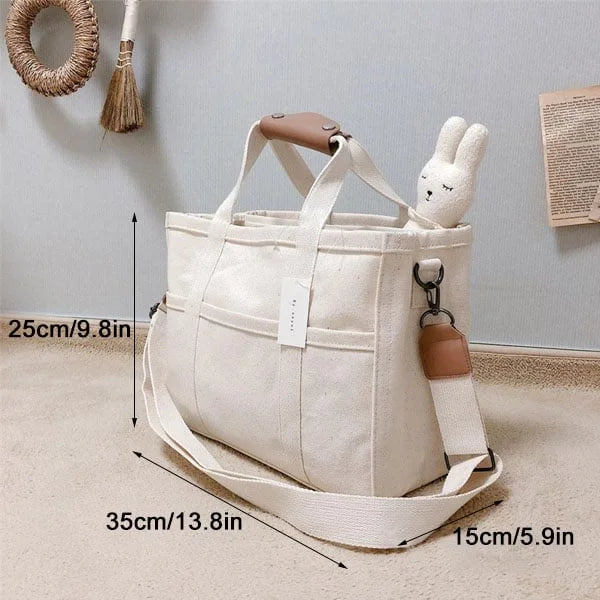Två eleganta bärkassar (beige & svart) sida vid sida, visar mångsidigheten hos denna stilfulla unisex axelväska.