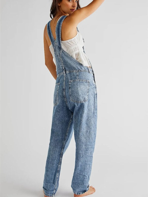 Helkroppsbild av dam jeansoverall. Blå denim jumpsuit med knappslå och fickdetaljer.