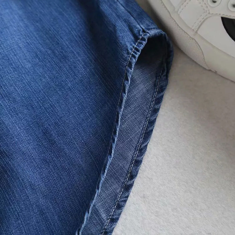 Baksida av blå dam denimskjorta, visning av ryggdetaljer och längd.