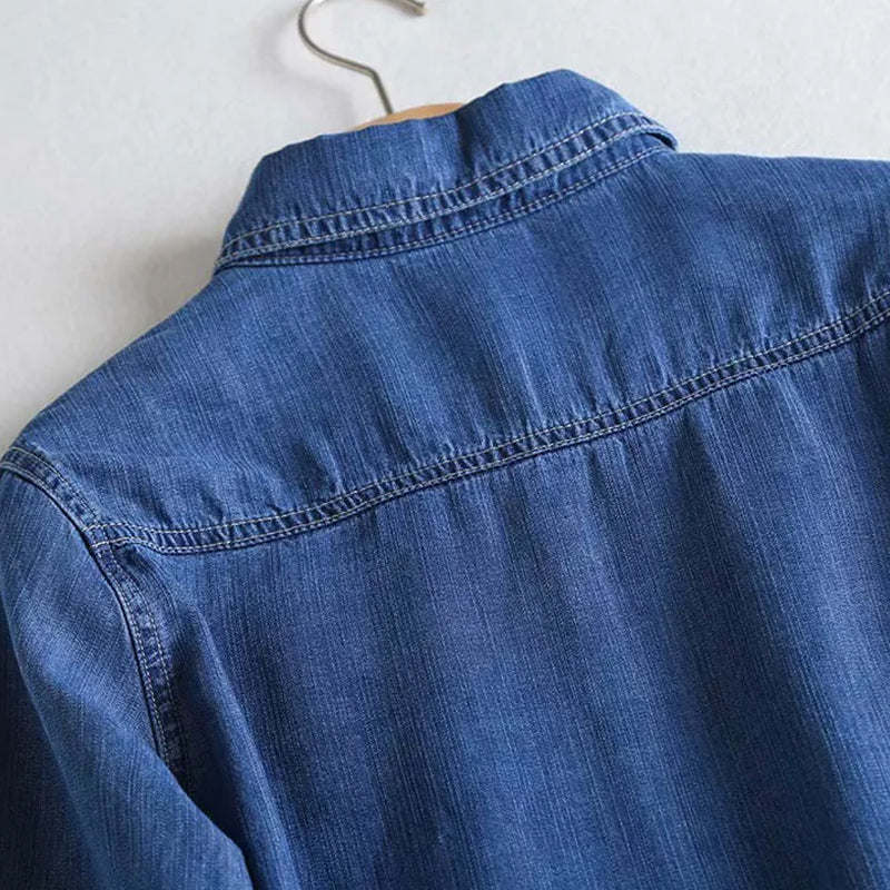 Närbild av kragen och knäppningen på den blå dam denimskjortan.