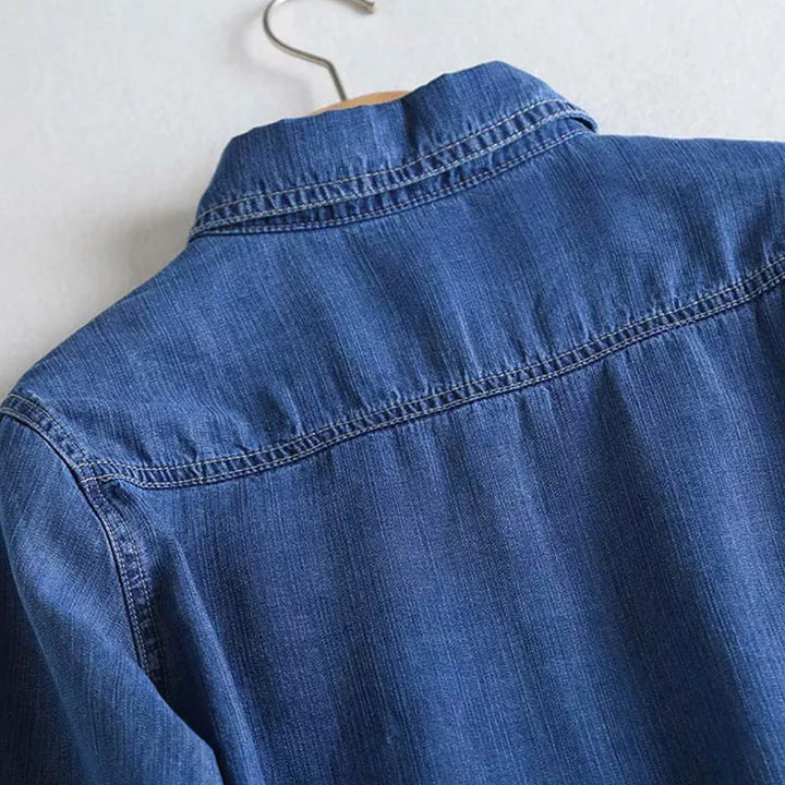 Närbild av kragen och knäppningen på den blå dam denimskjortan.