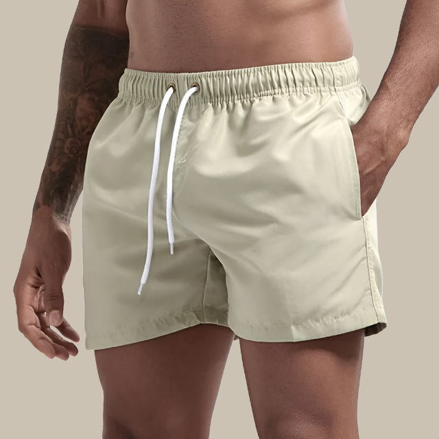 Herr i bekväma beigea badshorts med vit dragsnöre vid midjan