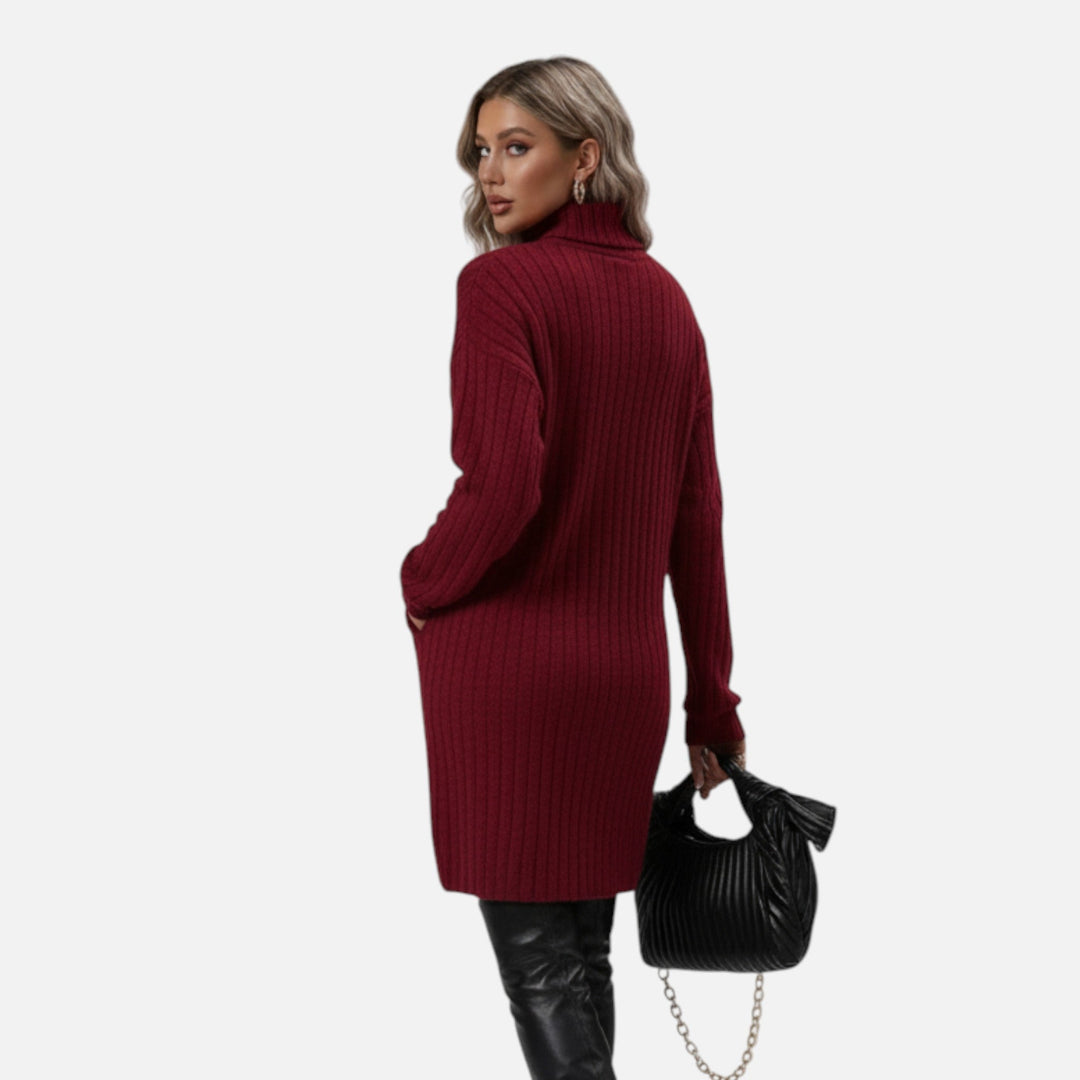 Bakifrån av modell i vinröd turtleneck stickad klänning med handväska