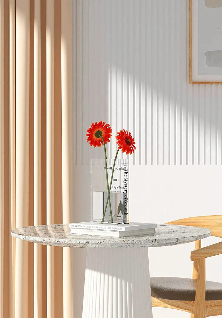 Rektangulär blomvas i bokdesign med röda blommor på vit yta