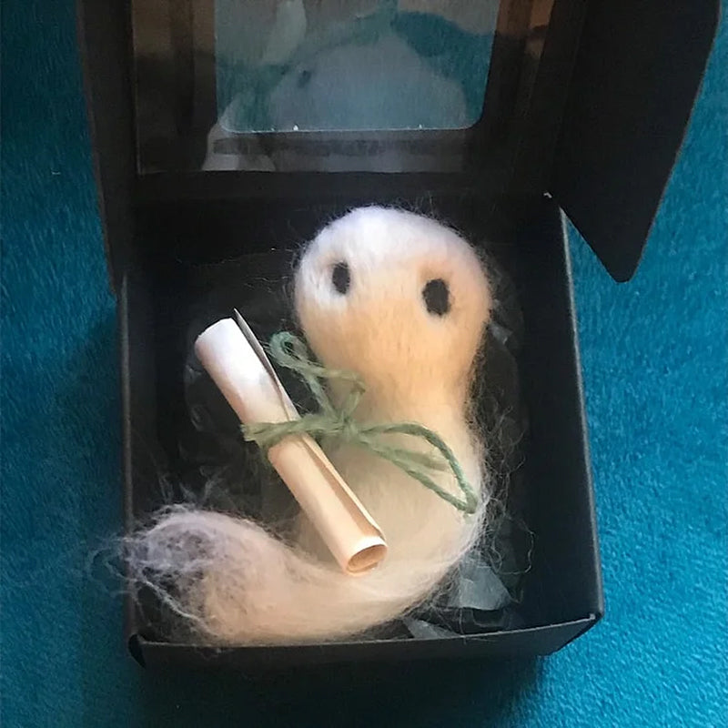 "Charmig handgjord filttom med unika detaljer, perfekt för Halloweendekoration, vilande i svart silkespapper."