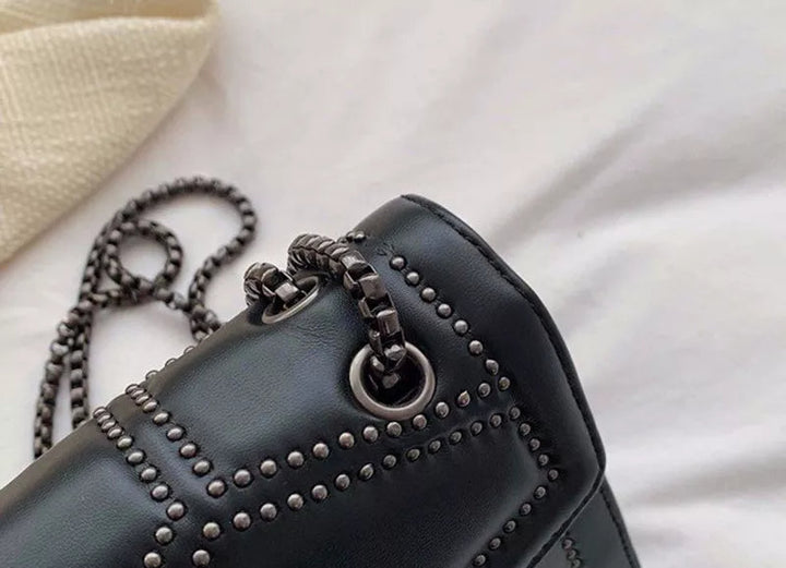 Högkvalitativ svart dam crossbodyväska. Nitad design, metallkedja & kompakt för dagligt bruk.