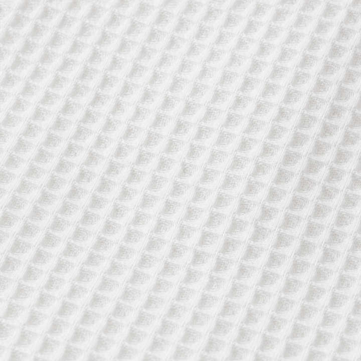Närbild på textur och knappar på våffelstickad damtröja med krage